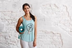 attractive woman holding green yoga or fitness mat after working out at home or in club