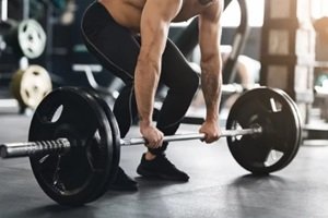 muscular powerlifter lifting heavy barbell from gym floor