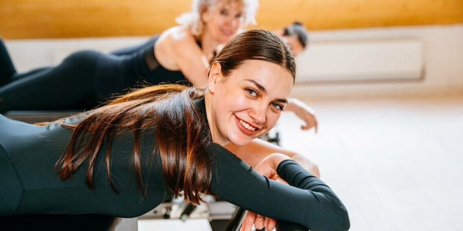 portrait of charming positive smiling caucasian woman pilates instructor lying relaxing on reformer bed