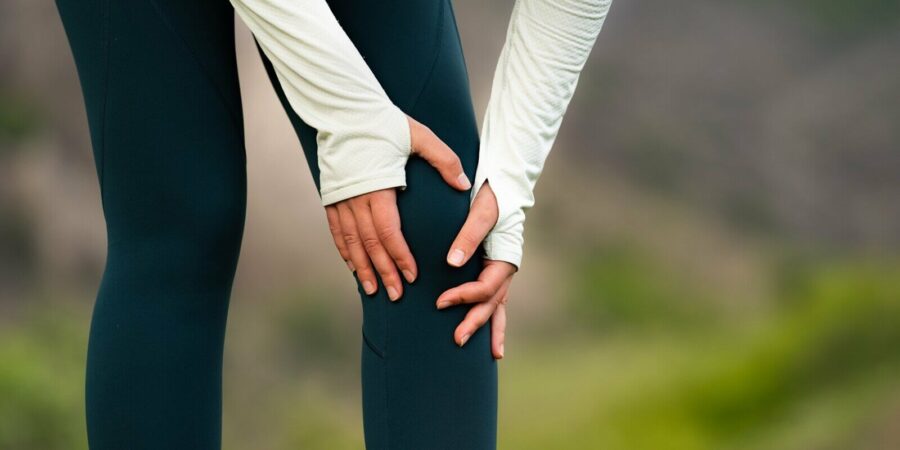 woman holding knee in pain after outdoor workout