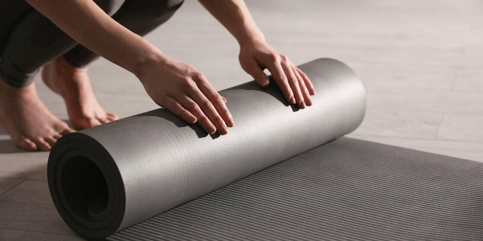 woman rolling yoga mat in studio